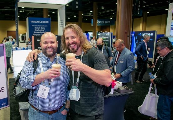 2 Conference attendees standing with rootbeer floats and smiling at the camera