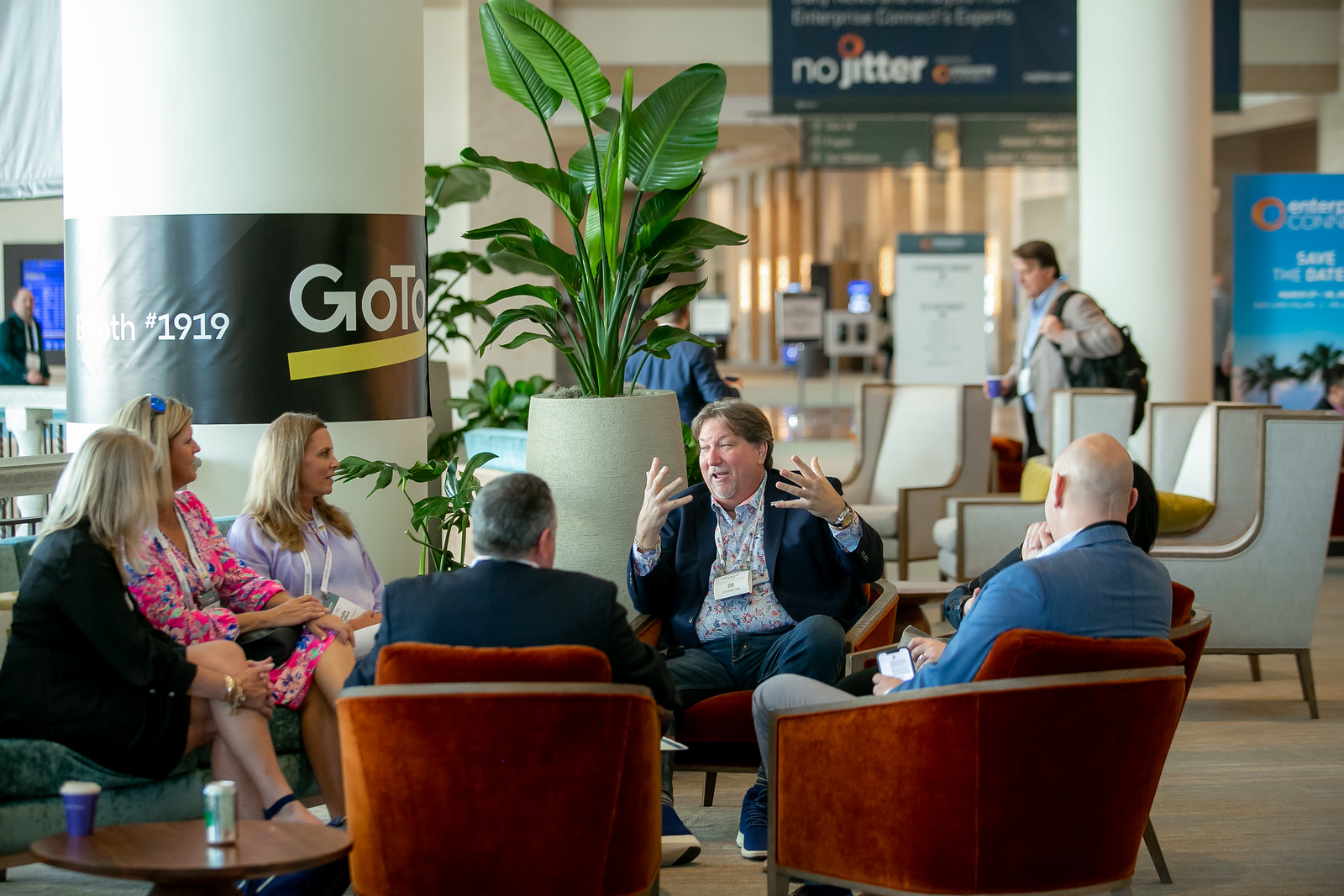 4 seated conference attendees in a networking lounge speaking with each other